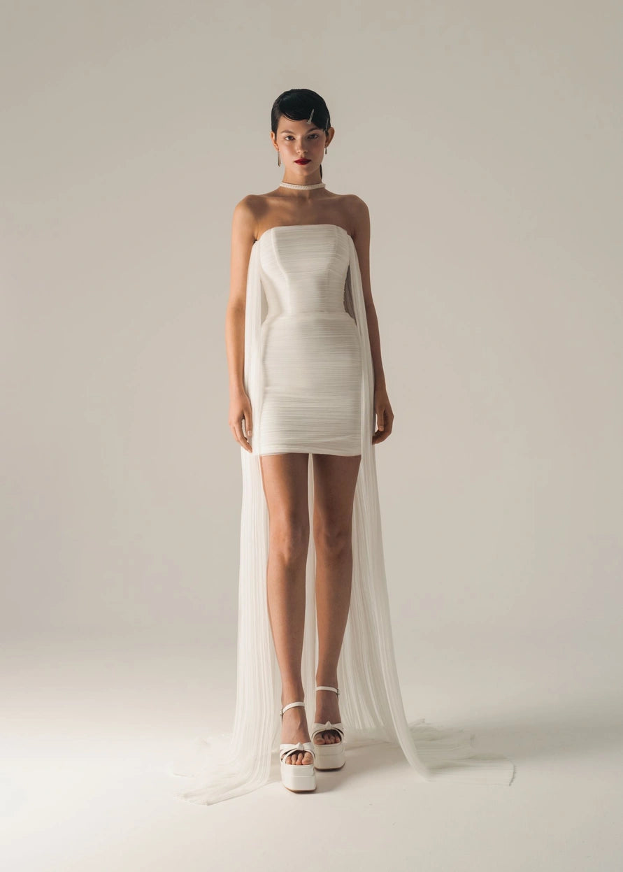 Short wedding dress with a long cape and a back with crossed shoulder straps.