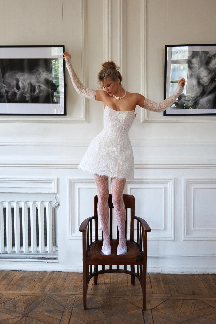 Robe de mariée courte avec de longues manches bouffantes et un dos ouvert avec une fermeture éclair.