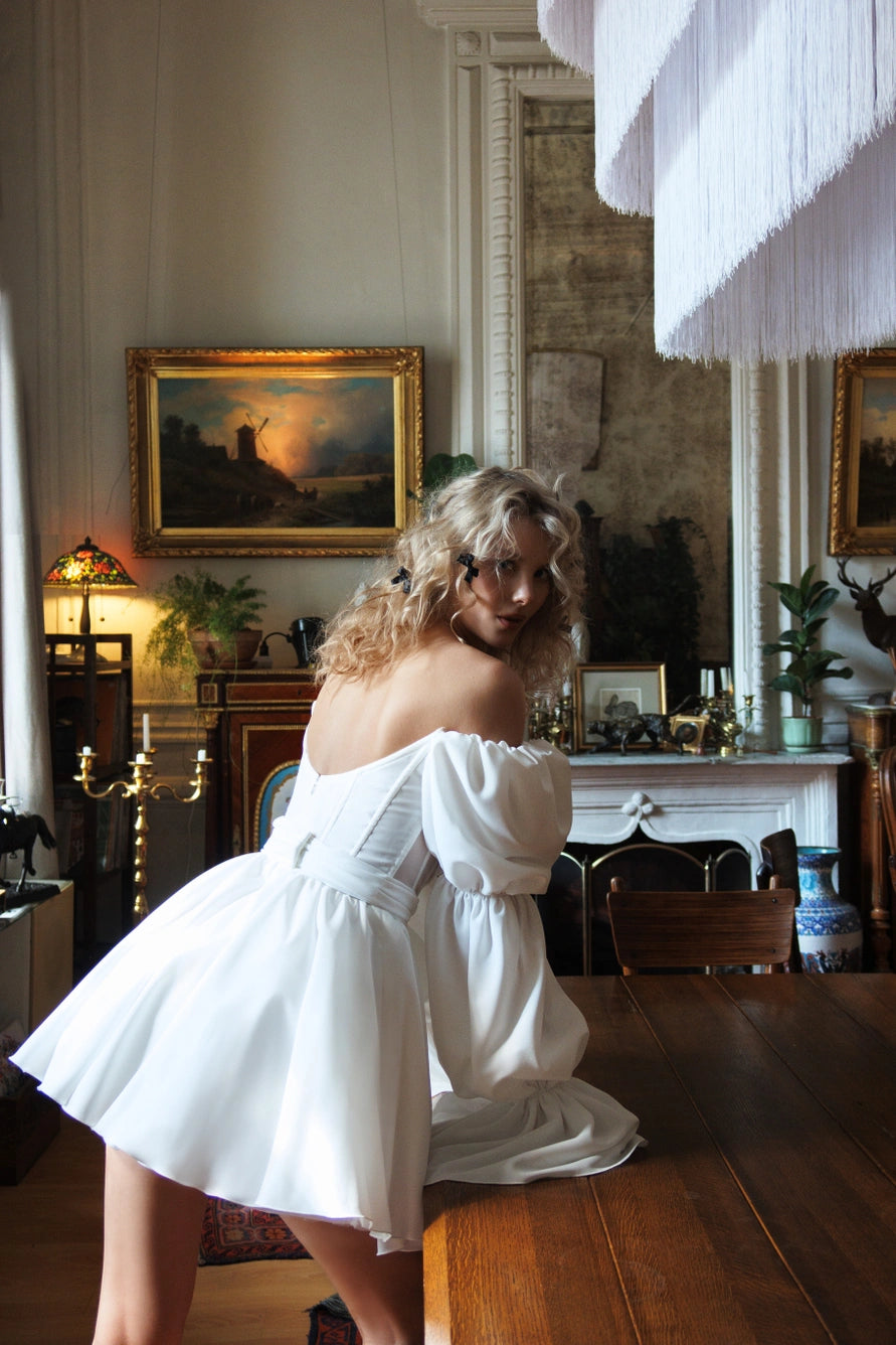 Short wedding dress with long puff sleeves and an open back with a zipper.