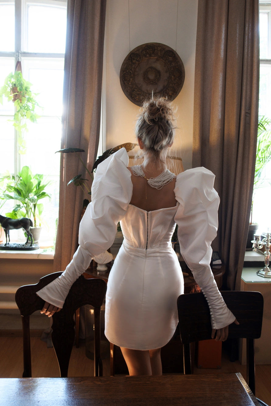 Short wedding dress with long puff sleeves and an open back with a zipper.