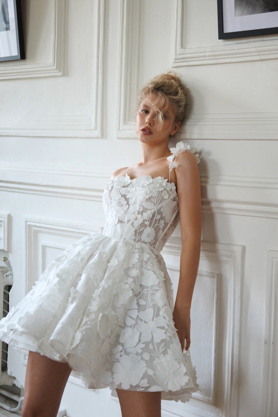 Robe de mariée courte avec de longues manches bouffantes et un dos ouvert avec une fermeture éclair.